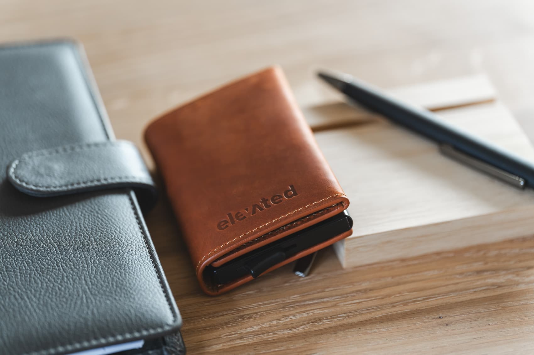 Valik Elevated ehtsast nahast kaarditaskuid, sealhulgas mudel KT004, stiilselt puidust laual.