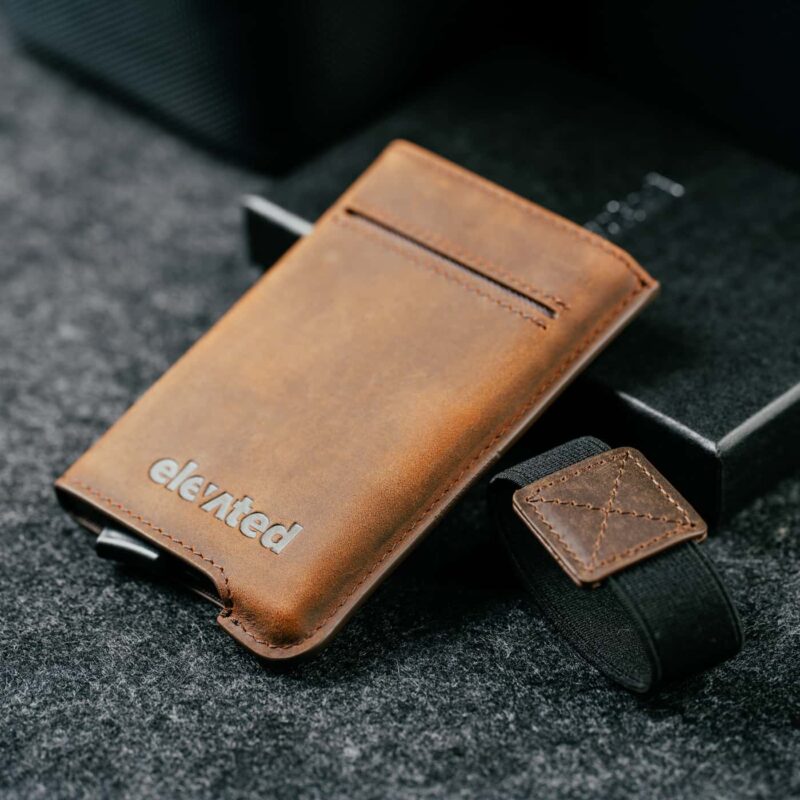 Elevated Extra Slim 1.0 pähklipruun kaarditasku koos eemaldatud elastse paelaga, näidates toote minimalistlikku disaini.