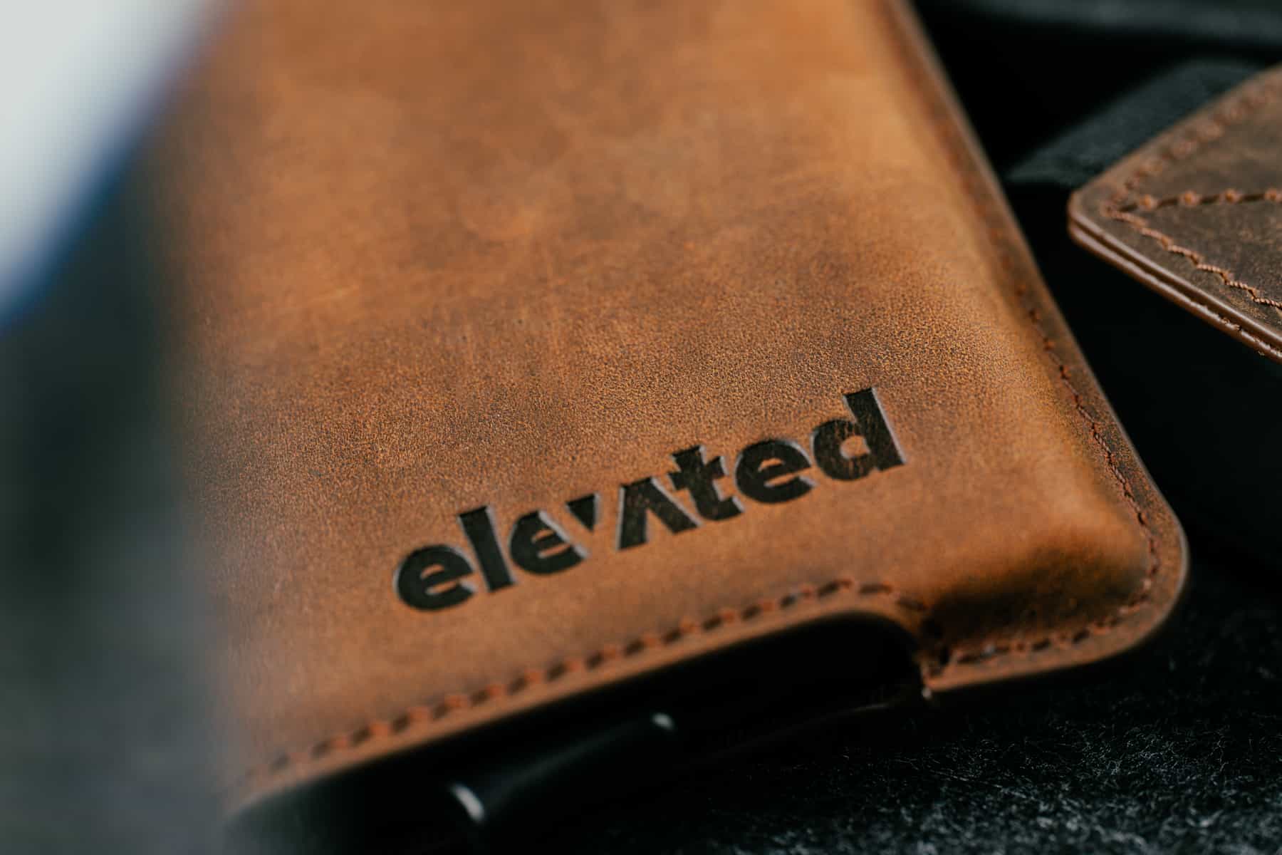 Lähivaade Elevated Extra Slim 1.0 kaarditasku pähklipruuni Crazy Horse naha unikaalsest tekstuurist ja pressitud logost.