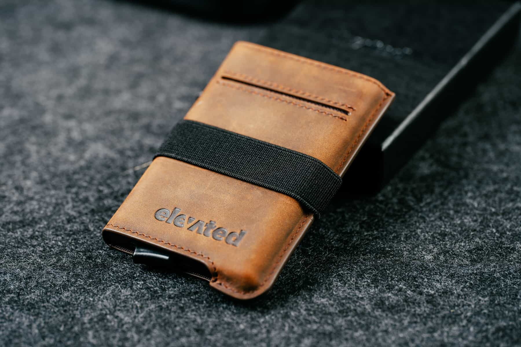 Pähklipruun Elevated Extra Slim 1.0 kaarditasku koos selle multifunktsionaalse ja eemaldatava elastse sularahapaelaga.
