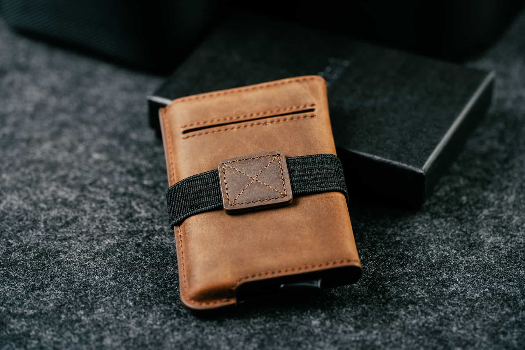 Elevated Extra Slim 1.0 kaarditasku pähklipruun variant stiilselt paigutatuna koos elegantse musta kinkekarbiga.