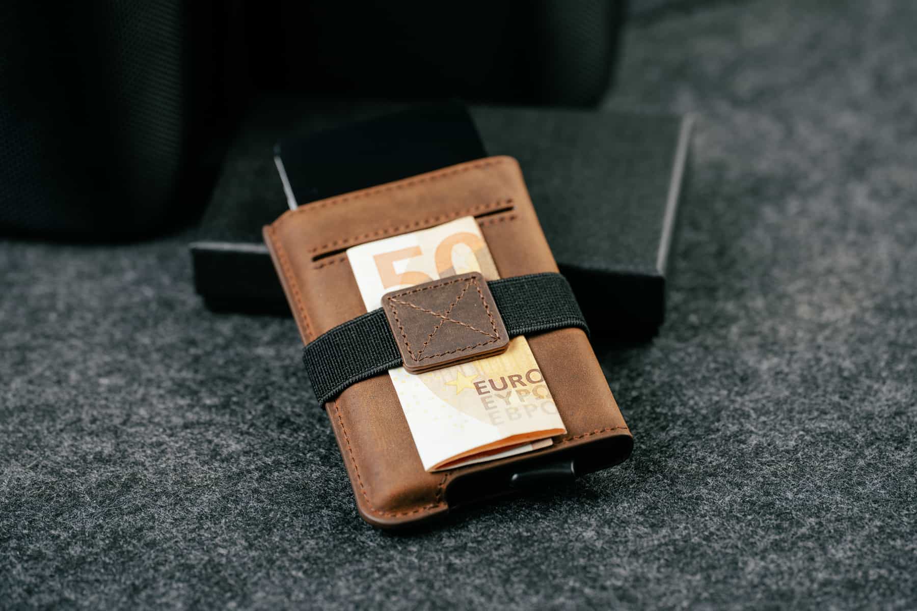 Elevated Extra Slim 1.0 kaarditasku elastne sularahapael hoidmas turvaliselt kokkuvolditud sularaha.