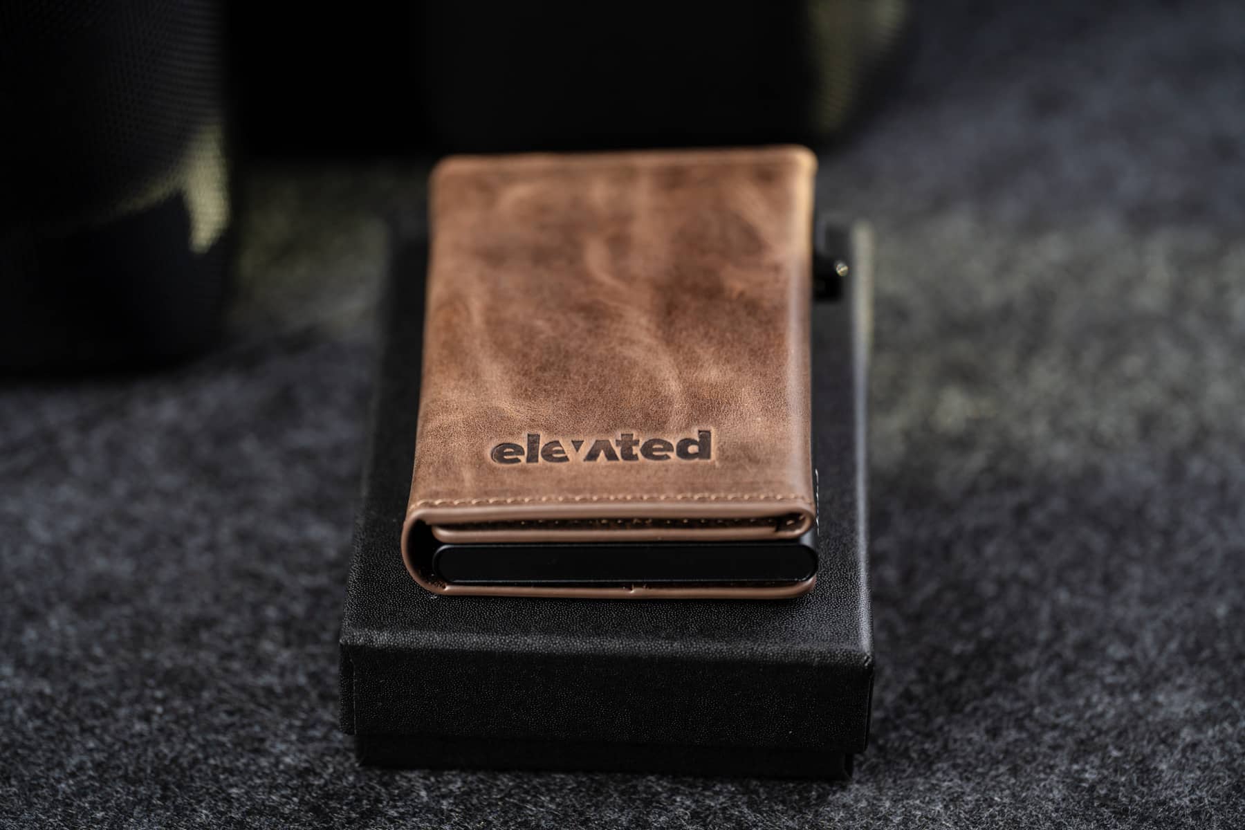 Šokolaadipruun Elevated Slim 2.1 kaarditasku asetatud elegantselt musta kinkekarbi peale. Ideaalne kingitus meestele ja naistele.