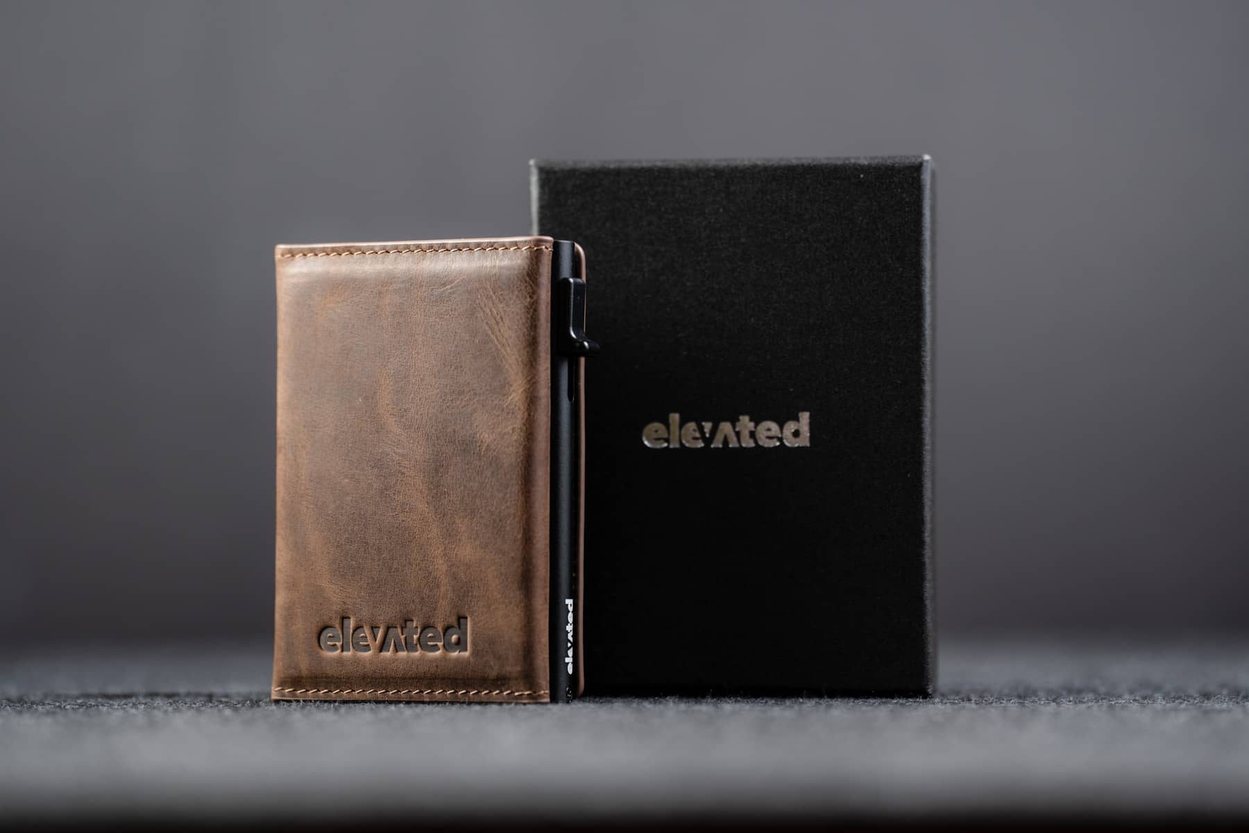 Otsevaates šokolaadipruun nahast kaarditasku Elevated Slim 2.1 koos musta kinkekarbiga. Stiilne ja praktiline kingiidee.