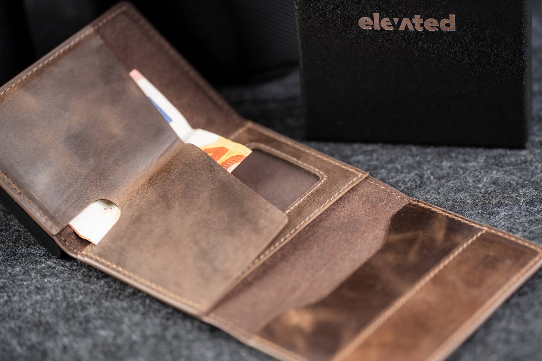 Avatud Elevated Slim 2.1 kaarditasku šokolaadipruunis toonis. Pildil on näha, kuidas sularaha ja lisakaardid taskutesse mahuvad.