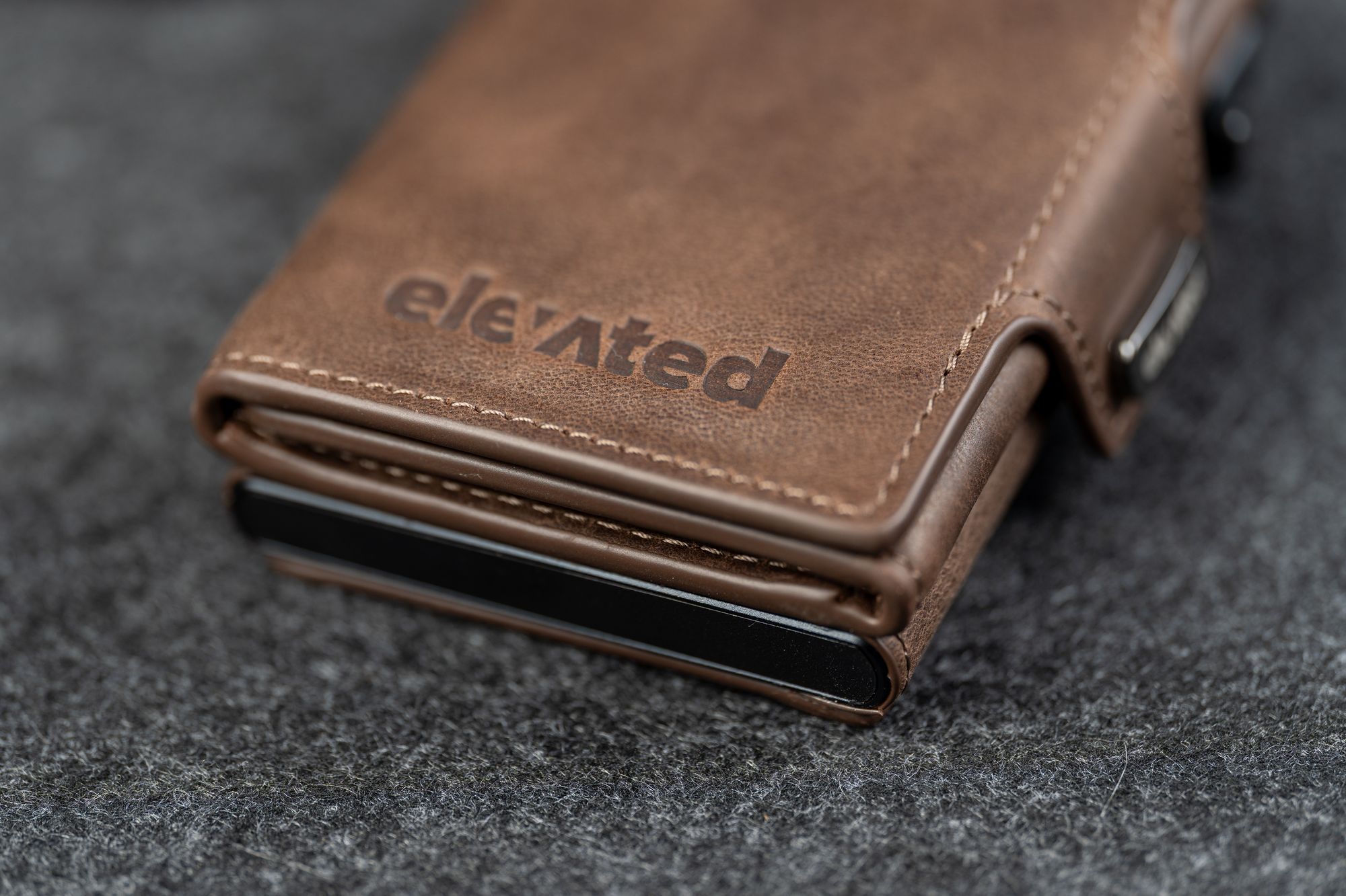 Kaarditasku Elevated Snap 1.0 Chocolate Brown, pressitud Elevated logo lähivaates